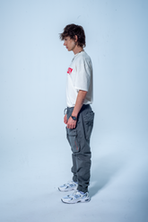 Model in the Haresquare vintage white tshirt with F*CK SOCIETY graphic print in red, styled with Haresquare gray cargo pants – unisex luxury streetwear from Ireland.